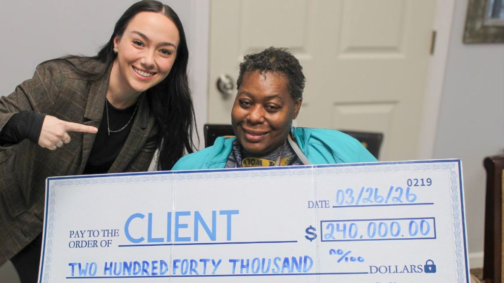 Client and paralegal holding a check for two hundred and forty thousand dollars