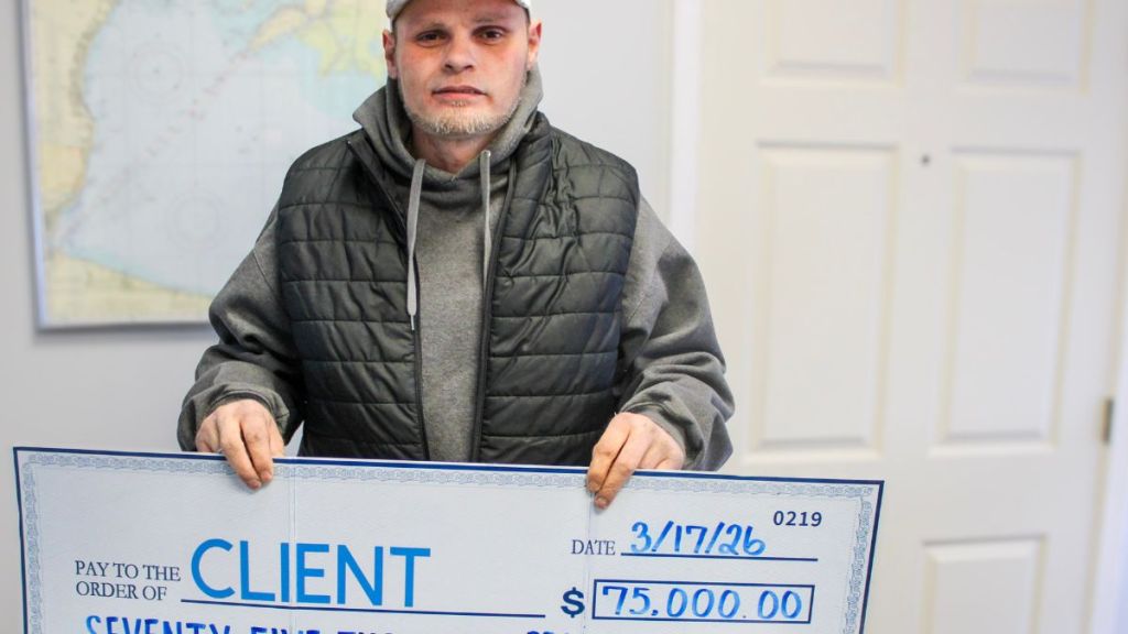Client holding a check for seventy five thousand dollars